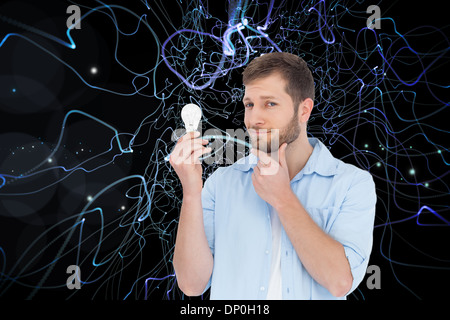 Composite image of handsome model holding a bulb Stock Photo