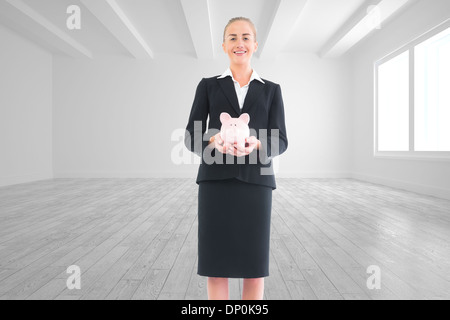 Composite image of businesswoman holding pink piggy bank Stock Photo