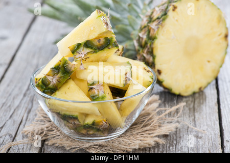 Pineapple Slices in a bowl on wooden background (close-up shot) Stock Photo