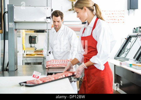 Butchers Processing Meat In Store Stock Photo