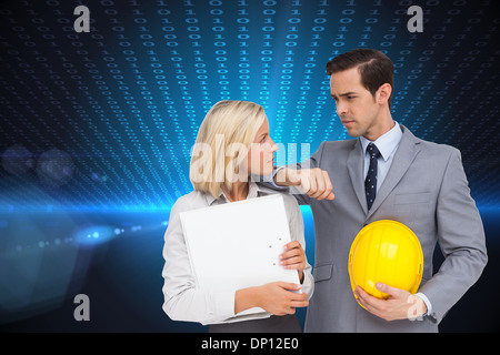 Composite image of architects with plans and hard hat looking at each other Stock Photo
