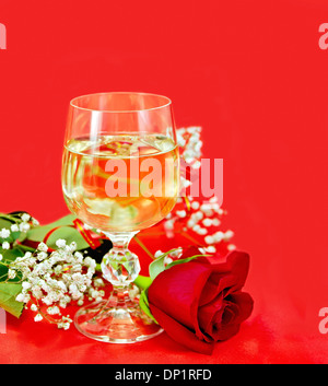 White wine in a glass with a rose on a red fabric Stock Photo