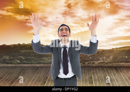 Composite image of excited businessman with arms raised Stock Photo