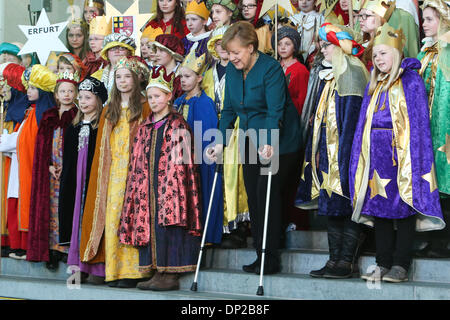 Berlin, Germany. 7th Jan, 2014. German Chancellor Angela Merkel (C) walks with crutches as she attends a reception with young carol singers at the Chancellery in Berlin, capital of Germany, on Jan. 7, 2014. German Chancellor Angela Merkel has injured her pelvis in a cross-country skiing accident in Switzerland and will have to cancel several meetings, her spokesman Steffen Seibert said on Monday. Credit:  Zhang Fan/Xinhua/Alamy Live News Stock Photo