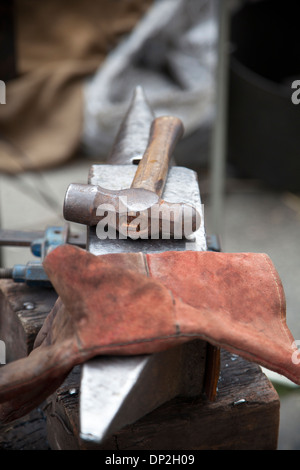 Old used hammer and glove on anvil. Stock Photo