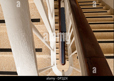 Vertigo anxiety and fear of heights a 6 floor stairwell trapped with steel blue handrail and dark and dingy flight of stairs Stock Photo