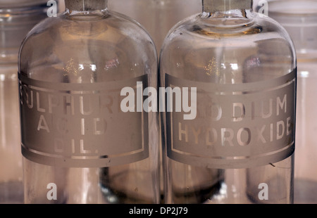 macro view of old glass chemistry bottles labeled for sulphuric acid diluted and sodium hydroxide Stock Photo