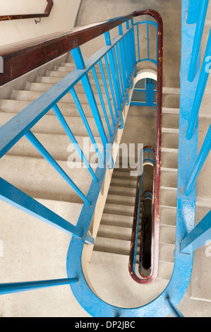 Vertigo anxiety and fear of heights a 6 floor stairwell trapped with steel blue handrail and dark and dingy flight of stairs Stock Photo