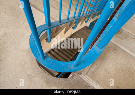 Vertigo anxiety and fear of heights a 6 floor stairwell trapped with steel blue handrail and dark and dingy flight of stairs Stock Photo