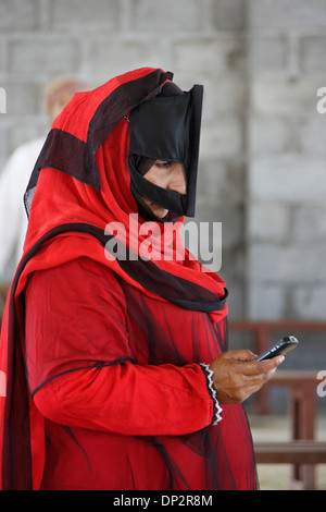 Bedu (Bedouin) woman checking cell phone, Sinaw, Oman Stock Photo