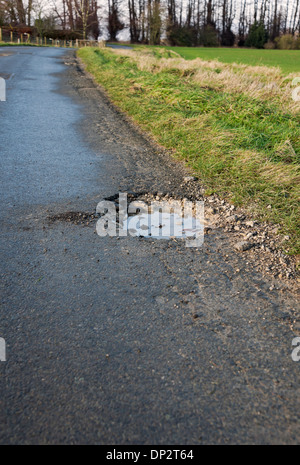 Pothole in the road lane filled with water in winter England UK United Kingdom GB Great Britain Stock Photo