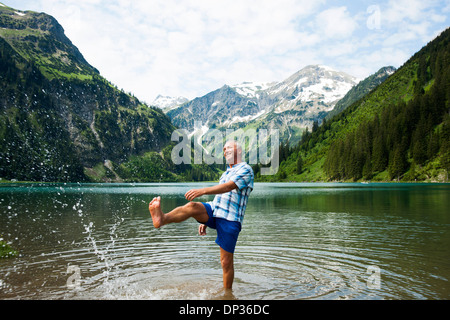 Mature man standing in lake, kicking water, Lake Vilsalpsee, Tannheim Valley, Austria Stock Photo