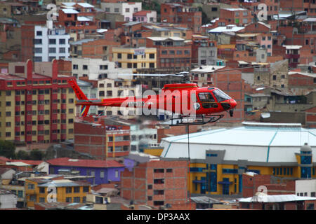 La Paz, Bolivia. 7th January 2014. A Eurocopter AS 350 B3 Ecureuil helicopter belonging to the Bolivian Air Force (FAB) carries a light synthetic cable between pylons, the first part of the process to install the final steel cable that will carry the gondolas for the new cable car / gondola lift currently under construction to link the cities of La Paz and El Alto. Three separate cable car lines are planned as part of an ambitious project to relieve traffic congestion, with the first line due to be completed by March 2014. Stock Photo