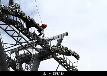 La Paz, Bolivia. 7th January 2014. A technician installs a light synthetic cable (that has been carried by helicopter) into position between rollers on a pylon. This is the first stage of the process to install the final steel cable that will carry the gondolas for the new cable car / gondola lift currently under construction to link the cities of La Paz and El Alto. The system is being built by the Austrian company Doppelmayr at a cost of $234.6 million financed by the Bolivian government. Credit:  James Brunker / Alamy Live News Stock Photo