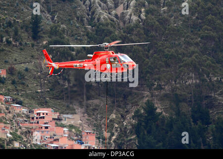 La Paz, Bolivia. 7th January 2014. A Eurocopter AS 350 B3 Ecureuil helicopter belonging to the Bolivian Air Force (FAB) carries a light synthetic cable between pylons, the first part of the process to install the final steel cable that will carry the gondolas for the new cable car / gondola lift currently under construction to link the cities of La Paz and El Alto. Three separate cable car lines are planned as part of an ambitious project to relieve traffic congestion, with the first line due to be completed by March 2014. Stock Photo