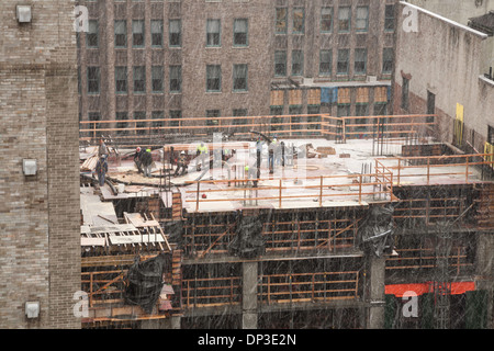 High-rise Building Construction Site with tradesmen in Snow Storm, NYC Stock Photo