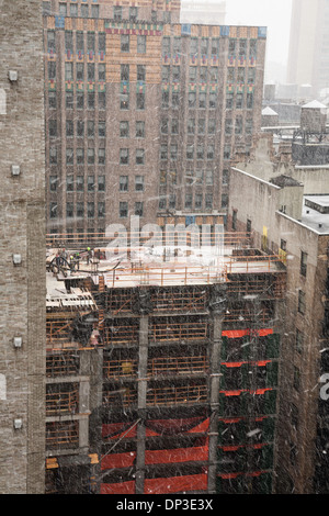 High-rise Building Construction Site with tradesmen, in Snow Storm,  NYC Stock Photo