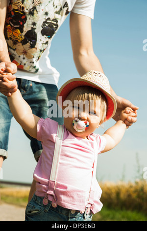 Father Holding Baby Daughter's Hands Outdoors, Mannheim, Baden-Wurttemberg, Germany Stock Photo