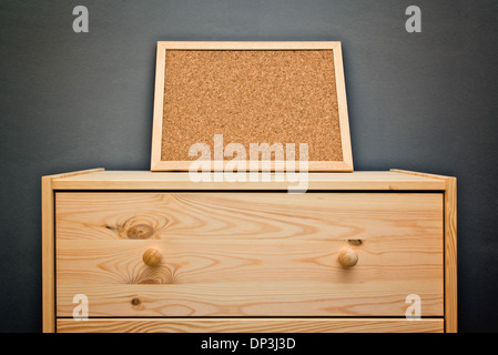 Empty cork memory board on wooden cabinet in a room with copy space. Stock Photo