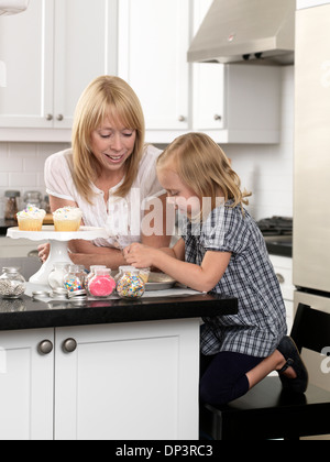 Mother and Daughter Decorating Cupcakes in open concept Kitchen, Toronto, Ontario, Canada Stock Photo