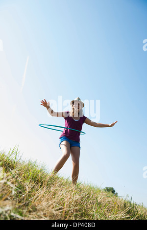 Girl using hula-hoop outdoors on hill, Germany Stock Photo