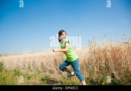 Girl running in field on hill, Germany Stock Photo