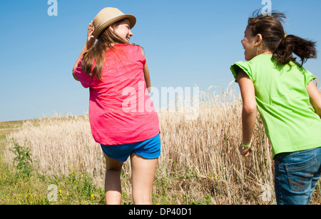 Backview of Girls running in field, Germany Stock Photo
