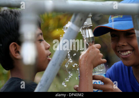 Jul 20, 2006; Ciamis, West Java, INDONESIA; Children staying at the refugee center in the hills of Pangandaran, West Java happily fill their drinking bottles with clean water. The villagers who survived the tsunami still worry about the possibilities of another earthquake and tsunami. A tsunami hit the coast of the Indonesian island of Java killing more than 550 people, leaving ove Stock Photo