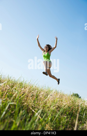 Teenaged girl jumping in mid-air in field, Germany Stock Photo