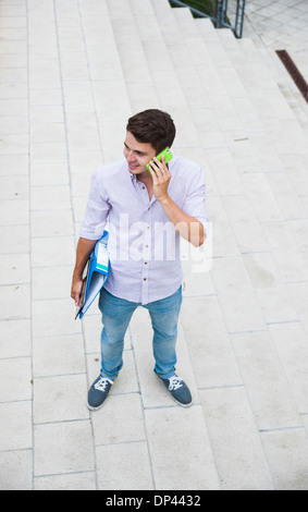 High angle view of young man standing outdoors, using cell phone, Germany Stock Photo