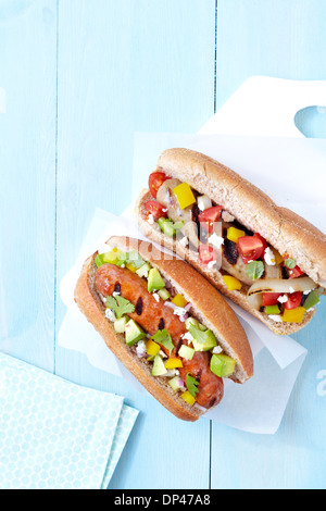 Overhead View of Grilled Sausages with Fresh Vegetable Toppings in Whole Wheat Buns, Studio Shot Stock Photo