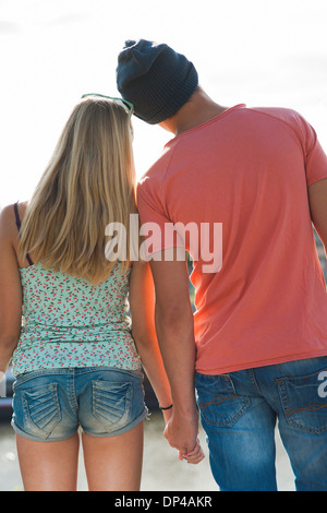 Backview of teenage boy and teenage girl holding hands, standing outdoors, Germany Stock Photo