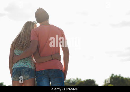 Backview of teenage boy and teenage girl with arms around each other, standing outdoors, Germany Stock Photo