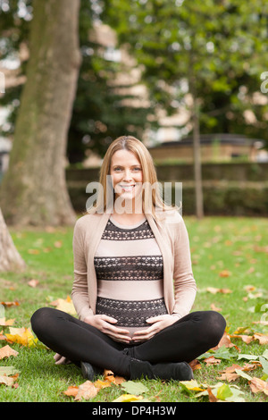 Pregnant woman sitting in park Stock Photo