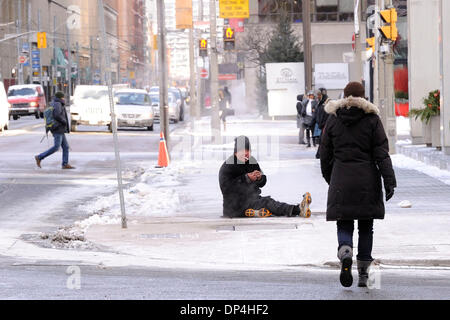 Toronto, Canada. 7th Jan 2014. A homeless man sits on a subway ventilation shaft in downtown Toronto to keep warm from the extreme cold temperature of near the minus 20 degrees Celsius mark. (Dominic Chan/EXImages) Credit:  EXImages/Alamy Live News Stock Photo