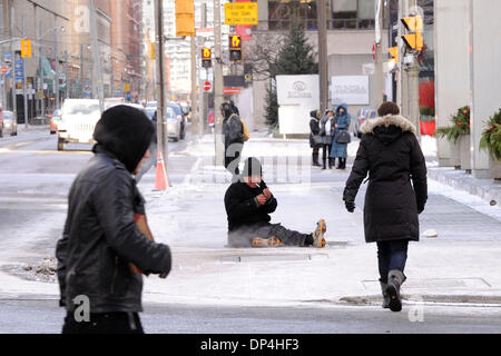 Toronto, Canada. 7th Jan 2014. A homeless man sits on a subway ventilation shaft in downtown Toronto to keep warm from the extreme cold temperature of near the minus 20 degrees Celsius mark. (Dominic Chan/EXImages) Credit:  EXImages/Alamy Live News Stock Photo