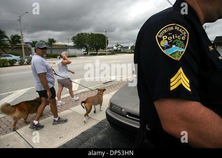 Aug 30, 2006; Boynton Beach, FL, USA; A couple walks their dogs down Federal Hwy. past Boynton Beach Police Sgt. Stewart Steele as he assits in making an arrest Wednesday morning, Aug. 30, 2006. The Department expected much more activity, the worst of which would come from Tropical Storm Ernesto. The habitually bad driver was taken into custody on running a red light, he had no lic Stock Photo
