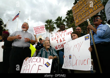 Sep 20, 2006; West Palm Beach, FL, USA; Bus drivers protested with signs and chants outside the school board office on Wednesday evening to complain about inaccurate paychecks and other problems. Shown here are (from left to right) Rev. Rick Riccard (standing), Sam Defeo (wheelchair), whose stepdaughter is a bus driver, and 8-year old Zsusie Carrillo, whose father is a bus maintena Stock Photo