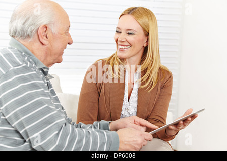 Smiling woman and senior man using tablet computer to surf the internet Stock Photo