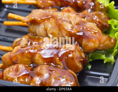 Chicken teriyaki with skewers inblack tray. Stock Photo