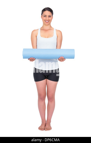 Cheerful slender model posing holding her rolled up mat Stock Photo