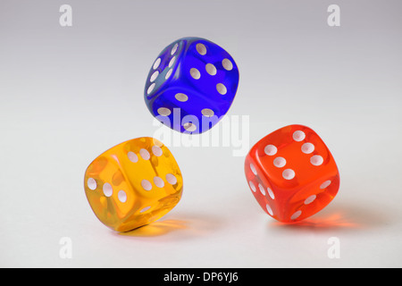 Three coloured plastic dice tumbling on a plain white background Stock Photo