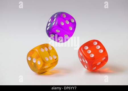 Three coloured plastic dice tumbling on a plain white graduated background Stock Photo