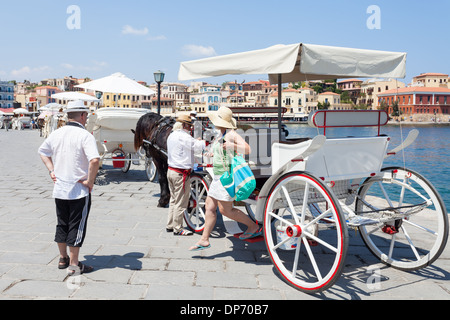 Tourists getting out a carriage in the Venetian Harbor of Chania after a tour for the Old Town, Crete Island, Greece Stock Photo
