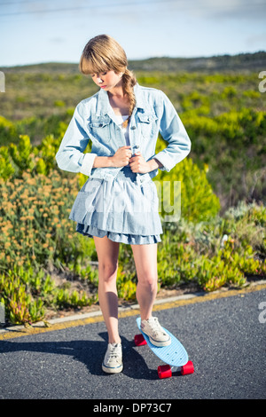 Attractive blonde skater posing on the roadside Stock Photo