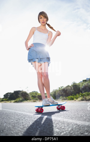 Astonished young woman balancing on her skateboard Stock Photo