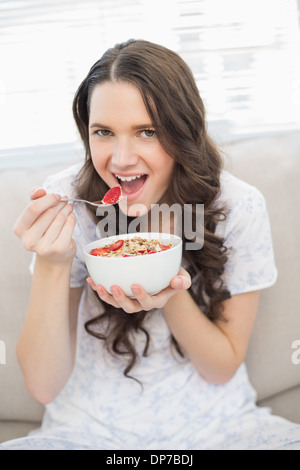 Pretty woman in pyjamas eating fruity cereal Stock Photo