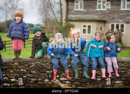 A group of country children sitting on a Cotswold stone wall at a meeting of the Beaufort Hunt in Didmarton, Gloucestershire UK Stock Photo