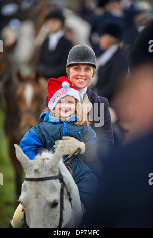 A horse rider gives her daughter a ride at a Christmas meeting of the Beaufort Hunt in Didmarton, Gloucestershire UK on Saturday Stock Photo