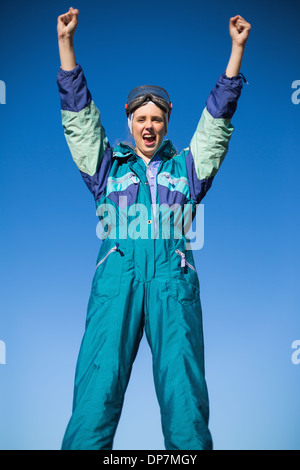 Woman wearing ski suit cheering Stock Photo